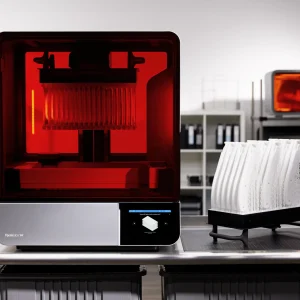 Formlabs Form 4BL während des Drucks, daneben fertig gedruckte Modelle auf einem Gestell