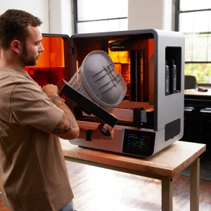 Mann entnimmt ein großes gedrucktes Bauteil an der Bauplattform aus dem Formlabs Form 4BL